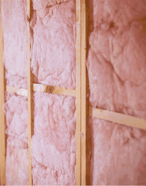 a wall with pink insulation on it and wooden beams