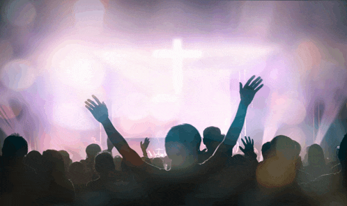 a crowd of people raising their hands in the air in front of a cross