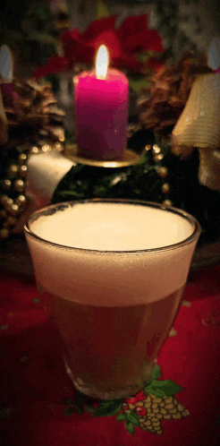 a purple candle is lit in a candle holder next to a glass of liquid