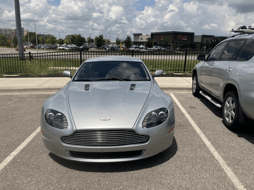 a silver car is parked in a parking lot next to another car