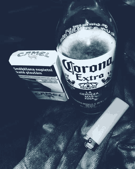 a bottle of corona extra next to a pack of camel cigarettes and a lighter