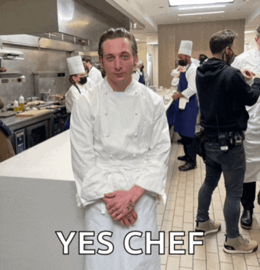 a man in a chef 's uniform is standing in a kitchen with the words yes chef written below him