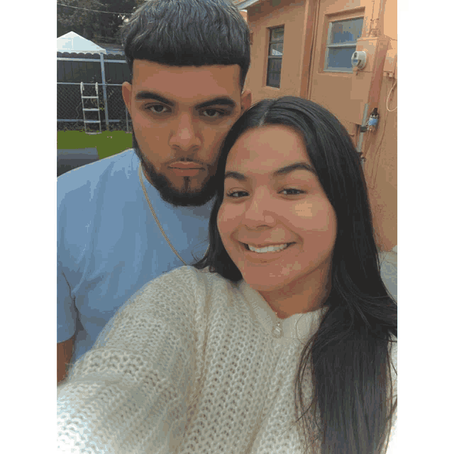 a man and a woman pose for a picture and the woman is wearing a white sweater