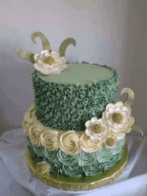 a green and white cake with flowers on it is on a table .