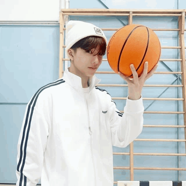 a boy wearing a white jacket and a white beanie holds a basketball