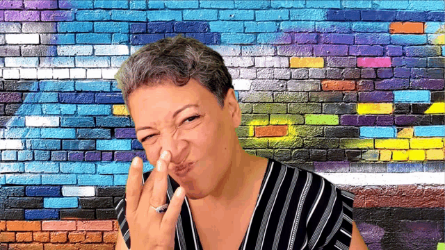 a woman is making a funny face in front of a brick wall