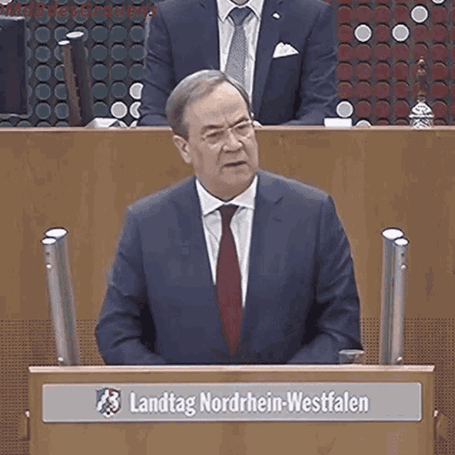 a man in a suit and tie is giving a speech in front of a podium that says landtag nordrhein-westfalen