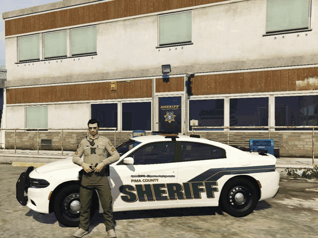 a man stands next to a pima county sheriff car