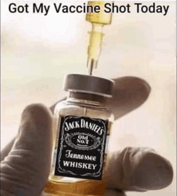 a person is holding a bottle of jack daniel 's whiskey with a syringe in it .