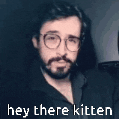 a man with glasses and a beard is saying hey there kitten