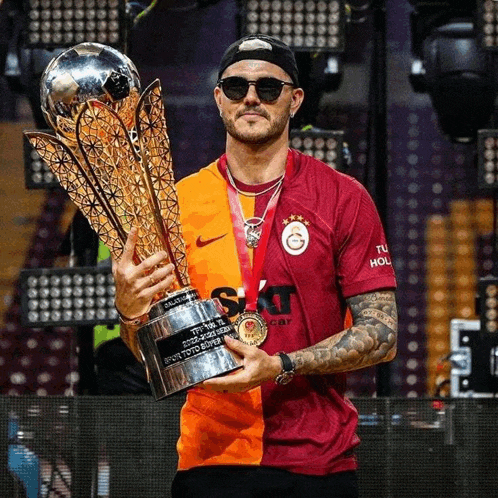 a man holding a trophy that says ' galatasaray ' on the front