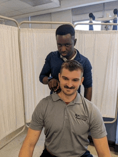 a man with a mustache is getting his neck examined by a doctor