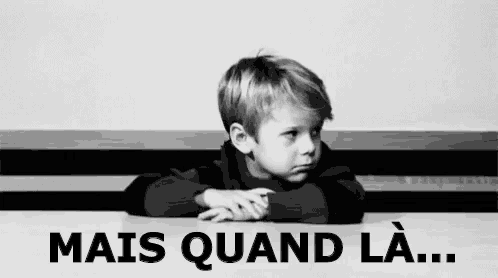 a black and white photo of a young boy sitting at a table with his hands on his head .