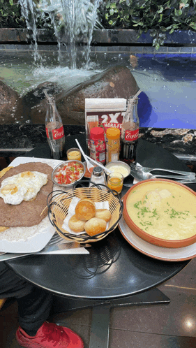 a bottle of coca cola sits on a table next to a bowl of food