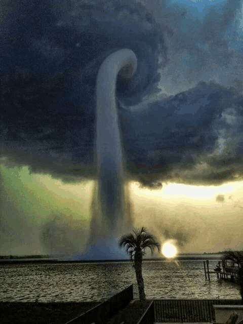 a large waterfall is coming out of a cloud over a body of water