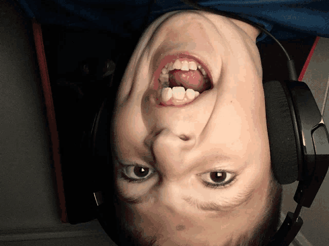 a young boy wearing headphones is upside down