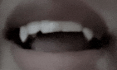 a close up of a person 's mouth with vampire teeth visible