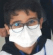 a young boy wearing a face mask and glasses is looking at the camera .