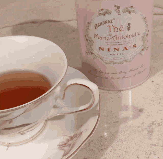 a cup of tea sits on a saucer next to a can of original the de marie-antoinette nina 's paris tea