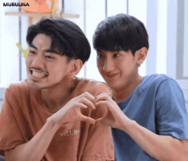 two young men are making a heart with their hands .