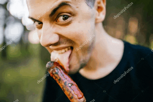 a man is sticking his tongue out while eating a barbecue sausage .