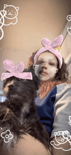 a girl wearing bunny ears and a mask holds a dog