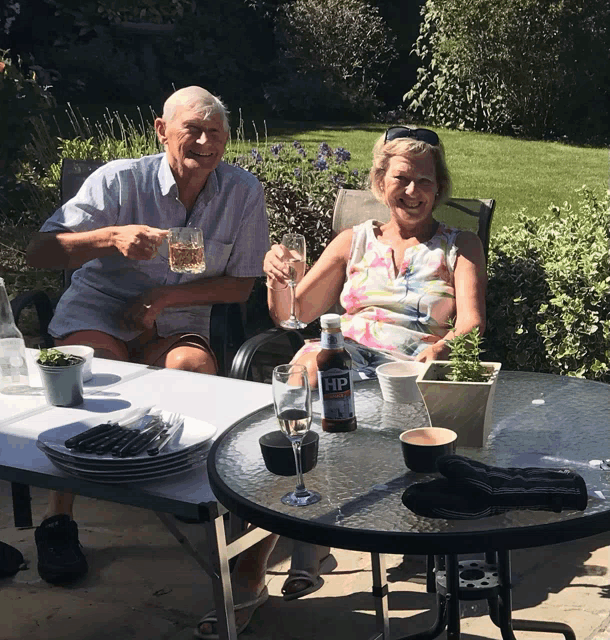 a man and a woman sitting at a table with a bottle of hp on it