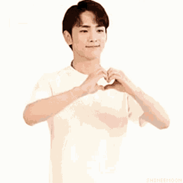 a young man is making a heart with his hands .