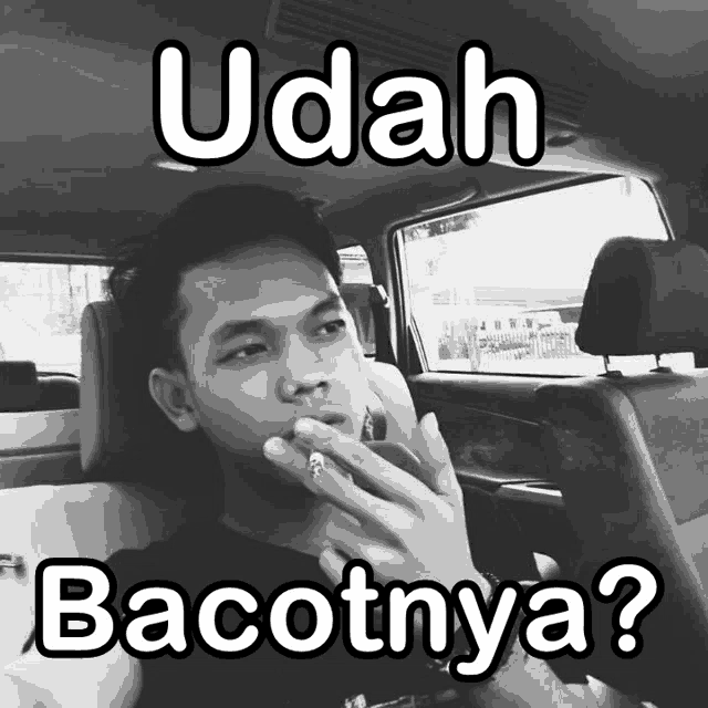 a man smoking a cigarette in a car with the words udah bacotnya below him