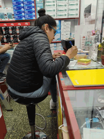 a woman in a black jacket sits in front of a display case with a yellow folder that says flash