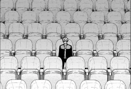 a man is standing in the middle of a row of empty seats in a theater .