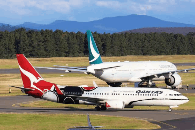 a qantas airplane is parked next to a cathay pacific plane