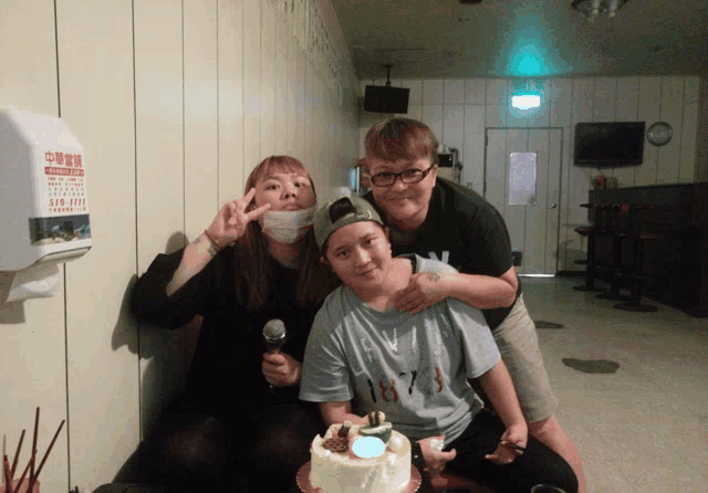 three people posing for a picture in front of a paper towel dispenser