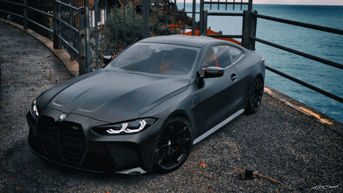 a black bmw is parked near the ocean