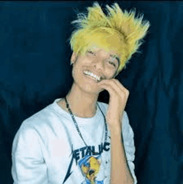 a young man with yellow hair is wearing a metallica t-shirt .