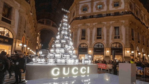 a gucci christmas tree is lit up in front of a prada store