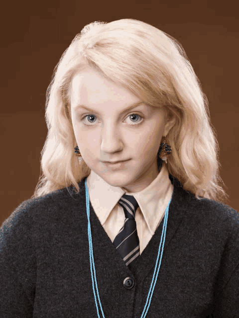 a girl with blonde hair and blue eyes is wearing a grey sweater and tie