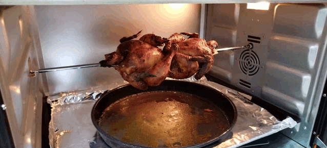 a chicken is cooking on a spit in an oven