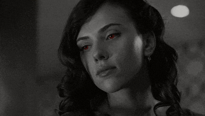 a black and white photo of a woman with red eyes looking at the camera .