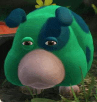 a green and blue cartoon animal is standing in the grass .