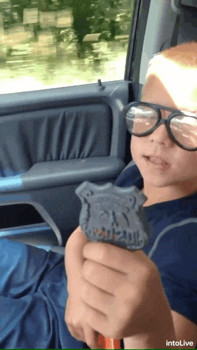 a young boy wearing glasses holds a police badge