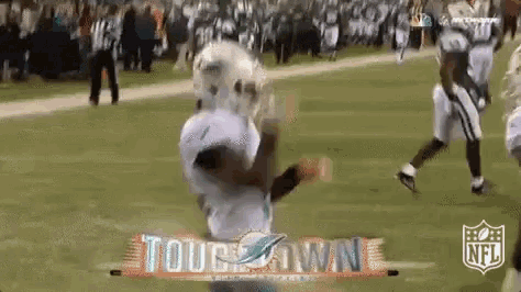 a football player is catching a ball on a field in front of a sign that says tough town .