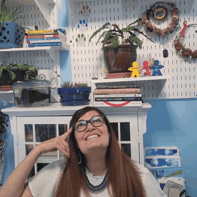 a woman wearing glasses is smiling in front of a shelf full of books including one titled what every girl is eating