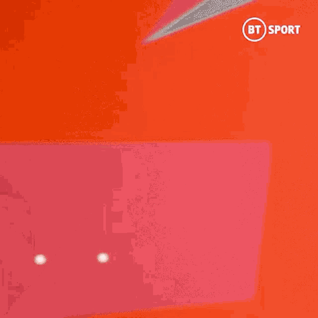 a blurry picture of a man wearing a red shirt with the bt sport logo on the bottom right