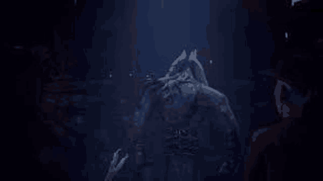 a man is standing next to a statue of a wolf in a dark room .