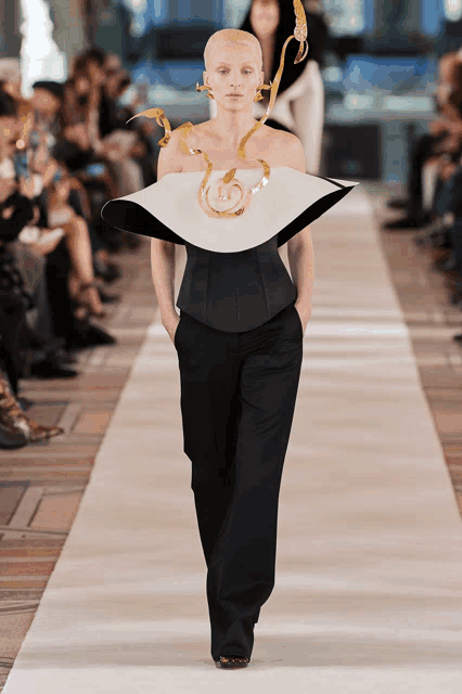 a model walks the runway at a fashion show wearing a black and white outfit