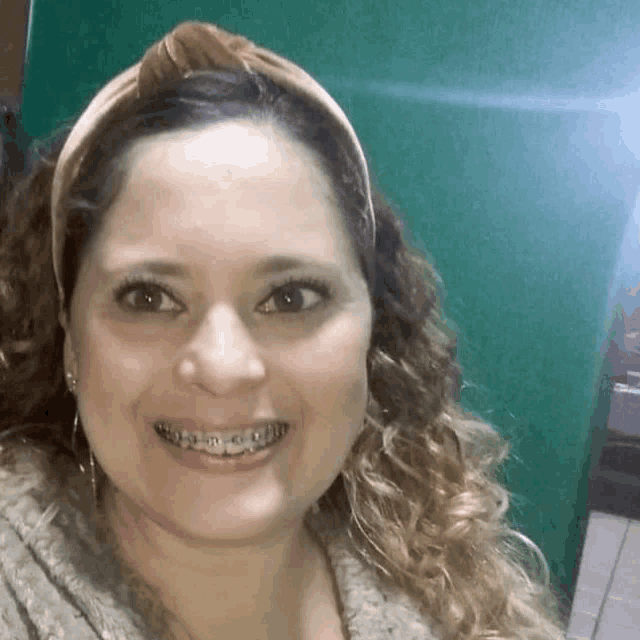 a woman with braces on her teeth is smiling for the camera while wearing a headband .