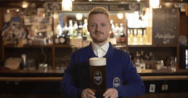 a man in a blue sweater is holding a glass of beer with a label that says ' giffel '