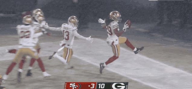 a football game between the 49ers and the green bay packers is being played in the rain