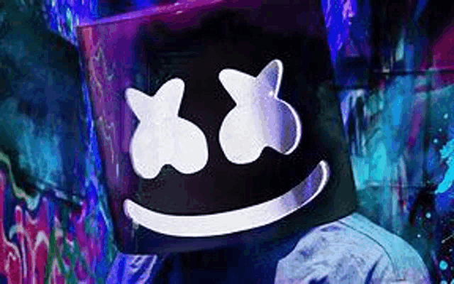 a man wearing a marshmello mask is standing in front of a graffiti covered wall .